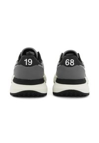 Sneaker grigie con accenti neri, realizzate in materiale morbido, con una suola intermedia bianca spessa e i numeri "19" e "68" sui talloni.