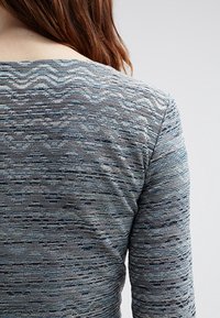 Košile s dlouhým rukávem s texturovaným pleteným vzorem v šedých a modrých odstínech, s kulatým výstřihem a mírně přiléhavým střihem.