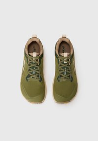 Baskets de sport vertes avec une tige en mesh texturé, des accents beiges et un design léger. Les caractéristiques incluent des lacets et une semelle rembourrée.