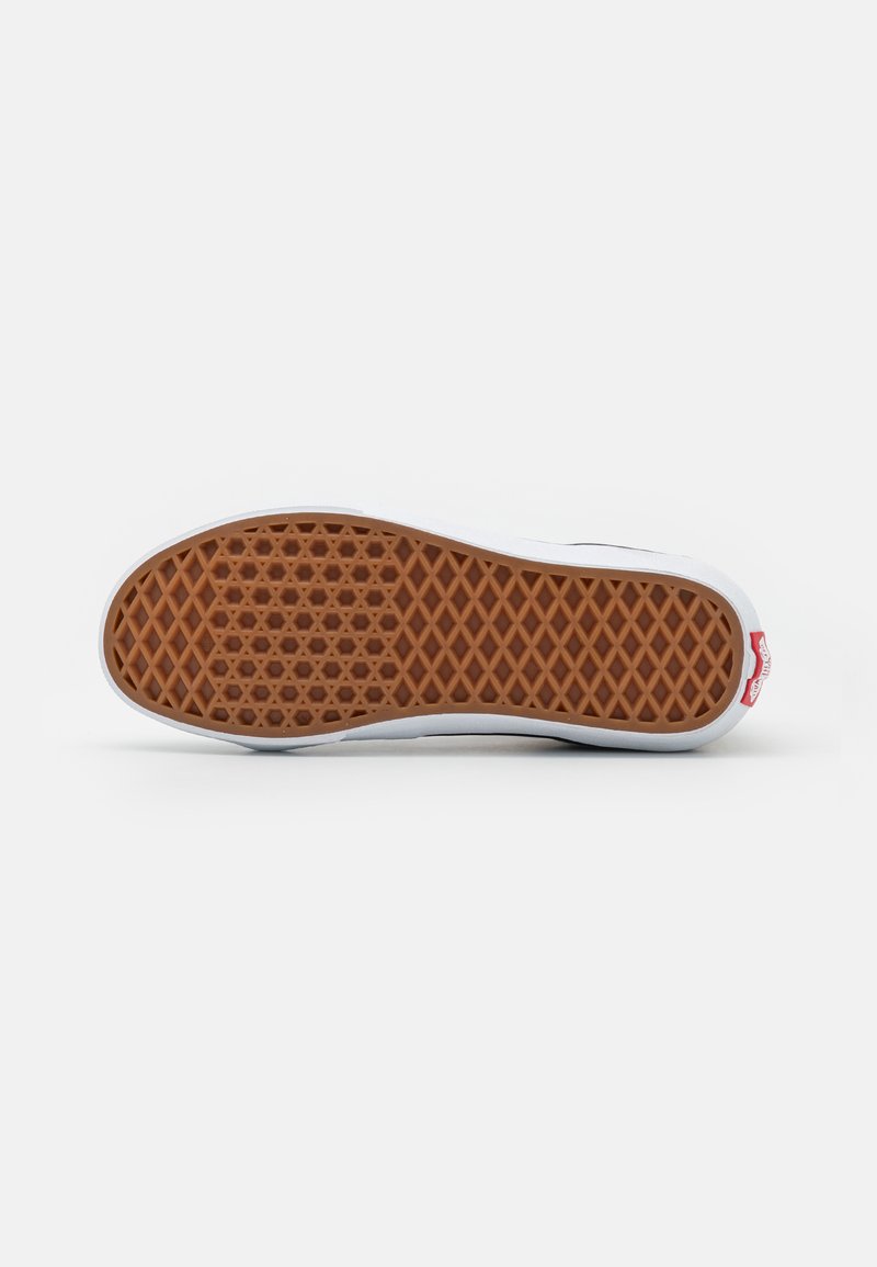 Zapatilla blanca con una suela de goma marrón texturizada, que presenta un patrón hexagonal y un detalle de logo en el lateral. Los bordes de la suela son redondeados.
