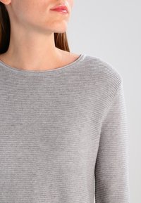 Hellgrauer Pullover mit Rundhalsausschnitt und strukturiertem Strick, langen Ärmeln und glatter Oberfläche.