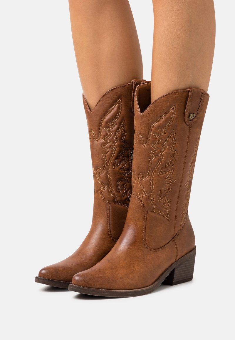 Bottes de cow-boy en cuir marron avec bout pointu et motifs de feuilles cousus, dotées d'un petit talon carré et d'une fermeture éclair latérale.