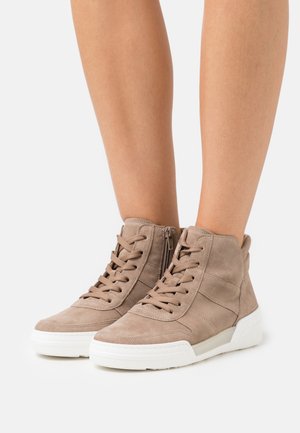 Vaaleanruske mokkanahkaiset korkeavartiset tennarit, joissa nauhat ja sivuvetoketju, käytetty paljaiden jalkojen kanssa, valkoisilla kumipohjilla.