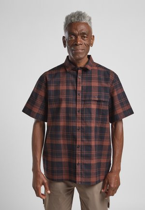 Camicia a maniche corte a quadri in marrone e nero, realizzata in tessuto dalla consistenza strutturata. Presenta una chiusura con bottoni e una tasca sul petto.