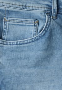 Jeans de mezclilla azul claro con un bolsillo trasero con costuras visibles, una textura suave y un diseño clásico. Detalles de áreas deslavadas en toda la prenda.