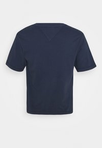 Granatowa, krótkiego rękawa koszulka położona na płasko, ukazująca tył z okrągłym dekoltem i trójkątnym przeszyciem poniżej kołnierza.