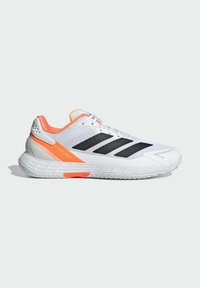 Λευκό αθλητικό παπούτσι με μαύρες ρίγες, πορτοκαλί λεπτομέρειες, επάνω μέρος από διχτυωτό ύφασμα, επενδεδυμένος γιακά και υφή στη σόλα. Σχεδιασμένο για ταχύτητα και απόδοση.