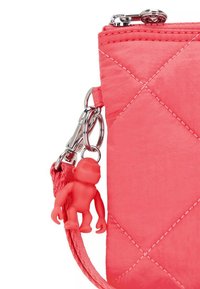 Quiltet koral håndtaske med glansfuld pink overflade, sølv hardware og en rød plastabekat charme fastgjort med en lobster clasp.