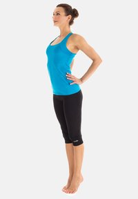 Women's activewear outfit featuring a fitted, sleeveless blue top and black capri leggings with a logo near the ankle. Smooth texture, athletic fit.
