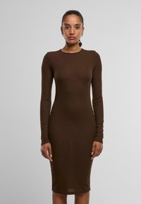 Robe marron à manches longues côtelées avec une silhouette ajustée, encolure ras du cou, atteignant le milieu du mollet. Texture lisse sans motifs ni accents visibles.