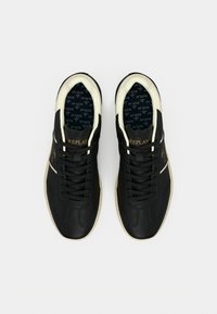 Paire de baskets de la marque Replay noir et blanc avec lacets, bordure intérieure crème et logo imprimé à l’intérieur des chaussures.