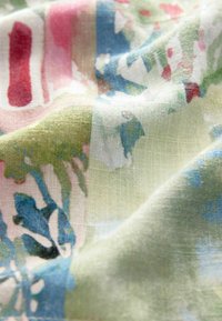 Textil mit einer weichen, leichten Webart, das ein Aquarellmuster in Grün, Blau, Pink und Weiß zeigt. Die Textur ist glatt und leicht transparent.