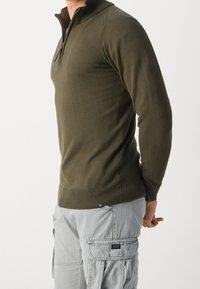 Olivgrüner Pullover mit langen Ärmeln und einem Viertelreißverschluss, mit gerippten Bündchen und Saum. Glatte Textur, körpernahe Passform.