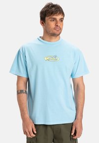 Light blue cotton t-shirt with a round neckline and short sleeves, featuring a yellow graphic print of a wave on the chest.