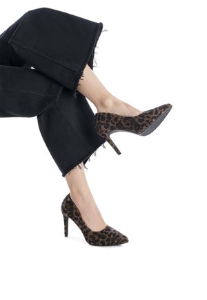 Zapatos de tacón alto con estampado de leopardo, puntera afilada, tacón de aguja negro y tejido texturizado. Combinados con unos vaqueros anchos negros deshilachados.