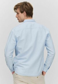 Lichtblauwe langek mouwen shirt met een button-down kraag en manchetten, een gladde textuur en een afgeronde zoom. Geen zichtbare patronen of hardware.