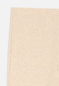 Beige ribbede leggins med en myk tekstur og elastisk livlinje. Har lette spraglete mønstre og pene sidesømmer.