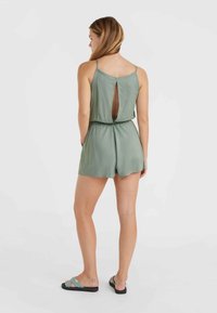 Mono sin mangas verde con corte en la espalda, cinturilla elástica y pantalones cortos. Textura suave y tirantes ajustables.