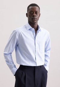 Camicia button-up a quadri blu chiaro e bianca con taschino, maniche lunghe e colletto classico, abbinata a pantaloni scuri.