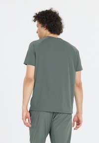 Harmaa urheilupaita, jossa on lyhyet hihat ja pyöreä kaula-aukko, valmistettu sileästä, kevyestä materiaalista, jossa on hieno tekstuuri.