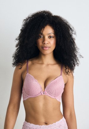 Reggiseno in pizzo rosa chiaro con bordo a scallop, supporto con ferretto, spalline regolabili e un dettaglio a fiocco decorativo al centro.