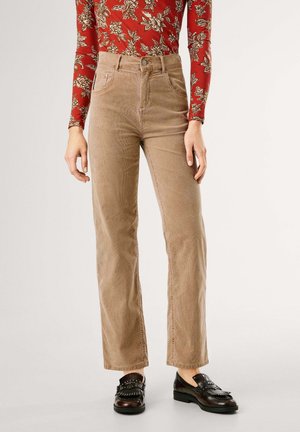 Person wearing high-waist beige corduroy pants, floral long-sleeve red top, and dark brown leather loafers with fringe and stud details.