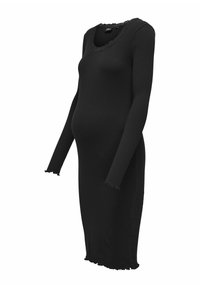 Robe noire à manches longues en tissu côtelé, avec un col festonné et des bords effilochés aux manches et à l'ourlet.