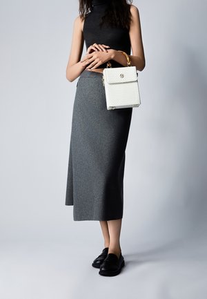 Falda midi de lana gris, top sin mangas de cuello alto negro, zapatos negros tipo mocasín y un bolso pequeño blanco con patrón texturizado y acentos dorados.