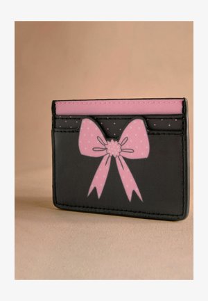 Čierny držiteľ kariet s dizajnom ružovej mašle. Obsahuje viacero slotov na karty a hladkú textúru. Prežívaný bielymi bodkami na mašli.