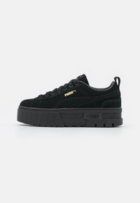 Schwarze Wildledersneaker mit dicker Plateausohle, schwarzen Schnürsenkeln, goldenen Logoakzenten und einer strukturierten Seitenfläche.