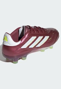 Scarpino da calcio color bordeaux con un design elegante. Presenta accenti bianchi e gialli, una finitura lucida e tacchetti traslucidi di un verde chiaro.