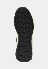 Sole di scarpa in gomma nera con un motivo a scanalature triangolari e un leggero bordo color crema. Presenta un'etichetta di marca al centro.