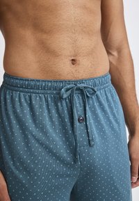 Hellblaue gemusterte Schlafshorts mit elastischem Bund, Bindegürtel und einem Knopfdetail an der Vorderseite. Weicher Stoff.