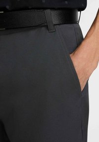 Grå skräddarsydda byxor i ett mjukt tyg, med en sidoficka och ett svart läderbälte med texturerad yta.