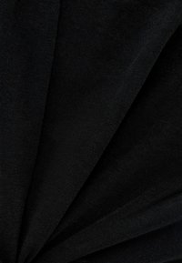 Czarna tkanina układa się w fałdy, prezentując gładką strukturę i głęboki kolor, tworząc elegancki, warstwowy wygląd.