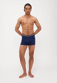 Navyblaue Boxer Shorts mit einem figurschmeichelnden Design und einem mehrfarbigen, gestreiften Elastikbund. Glattes Material und minimale Nähte.