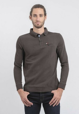 Polo shirt marron à manches longues avec un col, une patte de boutonnage et un petit détail de poche sur la poitrine. Texture de tissu douce.