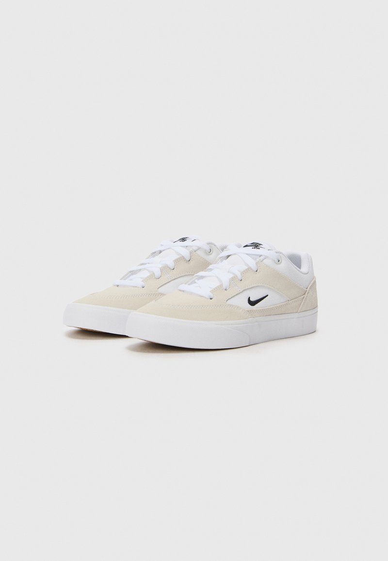 Zapatillas de ante beige con acentos blancos, que cuentan con una parte superior texturizada, cierre de cordones y un logo negro cerca del talón. Suela de goma plana.