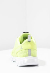 Reebok Sportschuhe in lebhaftem Neon-Gelb, mit Obermaterial aus Netzgewebe, strukturiertem Design und weißer Gummisohle mit grauen Akzenten und Ziehhilfe.