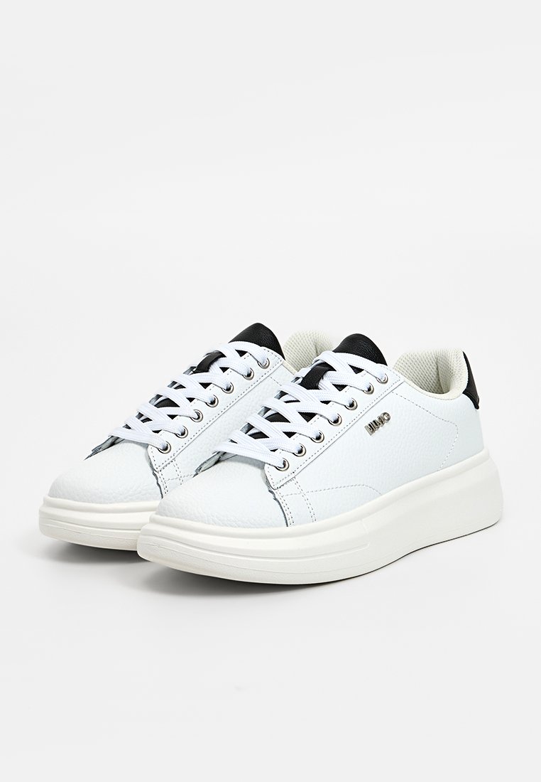 Zapatillas de cuero blancas con acentos negros y acabado texturizado. Presentan siete ojales, suela blanca gruesa y un diseño elegante.