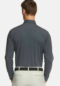 Graues Langarm-Polohemd mit traditionellem Kragen, aus glattem Stoff gefertigt, kombiniert mit hellen Hosen und einem schwarzen geflochtenen Gürtel.