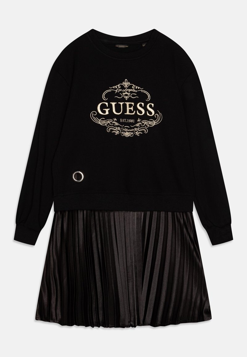 Schwarzes Sweatshirtkleid mit einem goldenen, gestickten "GUESS"-Logo, ergänzt durch einen gefütterten, satinähnlichen schwarzen Rock und einem silbernen, runden Akzentdetail.