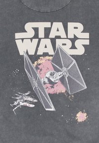 Mörkgrå T-shirt med texten "STAR WARS" och grafik av en TIE-fighter och en X-wing i rymden, med rosa och vita stänk.