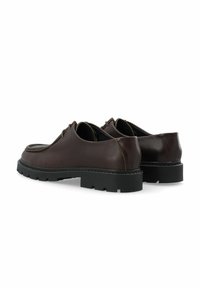 Zapatos de cuero marrón con punta redondeada, acentos cosidos y una gruesa suela de goma negra. Presentan un diseño elegante y un acabado texturizado.