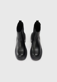 Bottines en cuir noir avec une finition lisse, des panneaux latéraux élastiques et un bout arrondi, dotées d'une semelle en caoutchouc noir robuste.