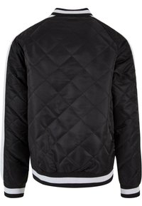 Black quilted bomber jacket with white striped ribbed cuffs and hem. Features a crew neckline and smooth texture, designed for casual wear.