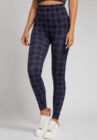 Marineblauwe leggings met een subtiele, gepatterneerde ontwerp met een herhalend logo, textuurstof, hoge taille, gecombineerd met witte sneakers.