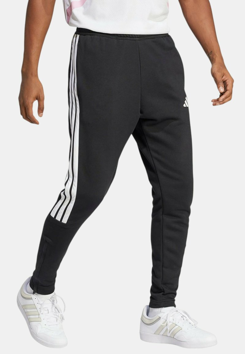 Pantaloni sportivi neri realizzati in tessuto morbido, con tre strisce laterali bianche, gambe affusolate e caviglie con zip per una facile vestibilità.