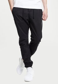 Pantalones jogger negros hechos de tela suave, con cintura elástica con cordón, piernas ajustadas y bolsillos laterales.