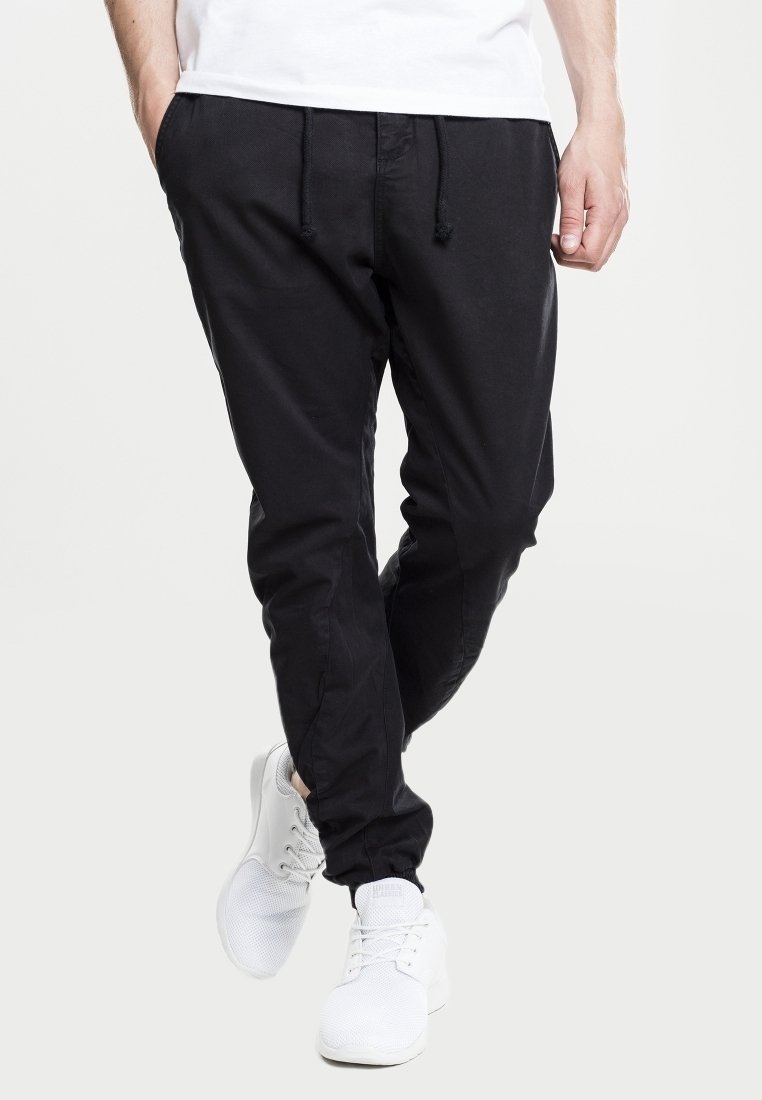 Pantalones jogger negros hechos de tela suave, con cintura elástica con cordón, piernas ajustadas y bolsillos laterales.